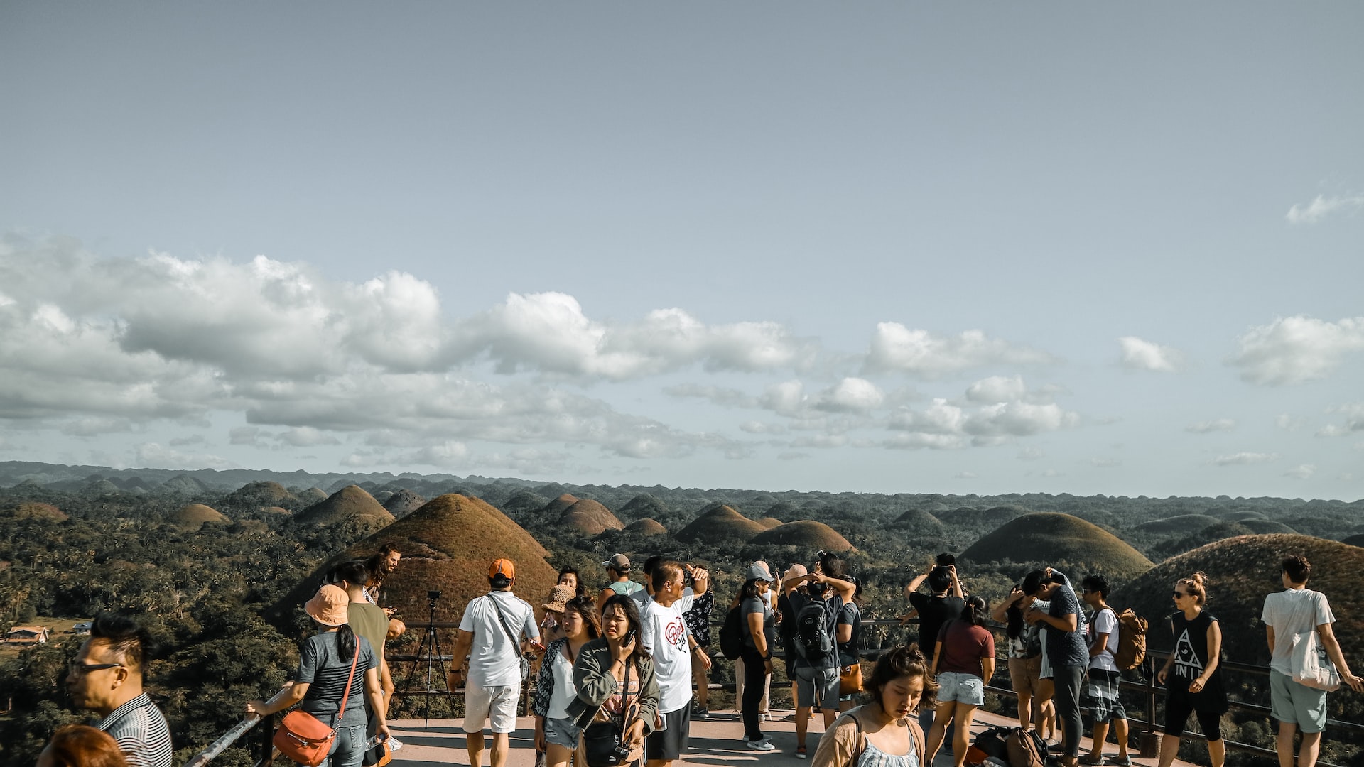 Local and foreign tourists in the Philippines looking at an aerial view of the Chocolate Hills in Bohol