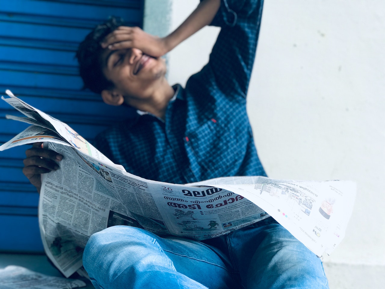 Man Sitting while Holding Newspaper